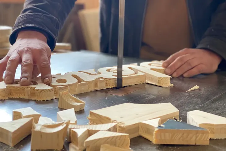 Holzbuchstaben werden an der Bandsäge ausgeschnitten